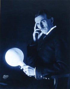 Nikola Tesla holding a light bulb, illuminated without wires by an electromagnetic field from the "Tesla Coil"