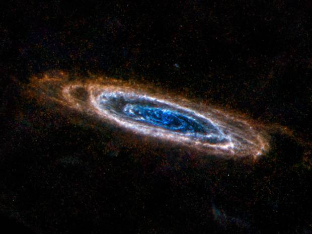 The ring-like swirls of dust filling the Andromeda galaxy stand out colorfully in this Herschel Space Observatory image via ESA/NASA/JPL-Caltech/NHSC