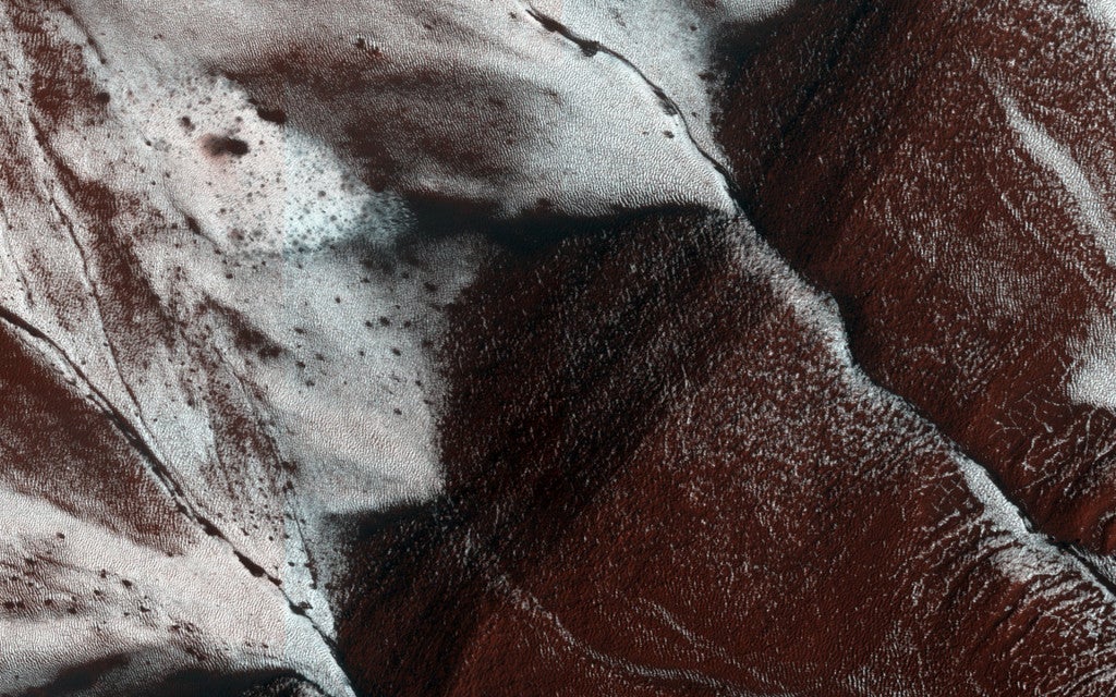 This newly released NASA image shows an area on the surface of Mars (approximately 1.5 by 3 kilometers in size) with frosted gullies on a south-facing slope within a crater. Image credit: NASA