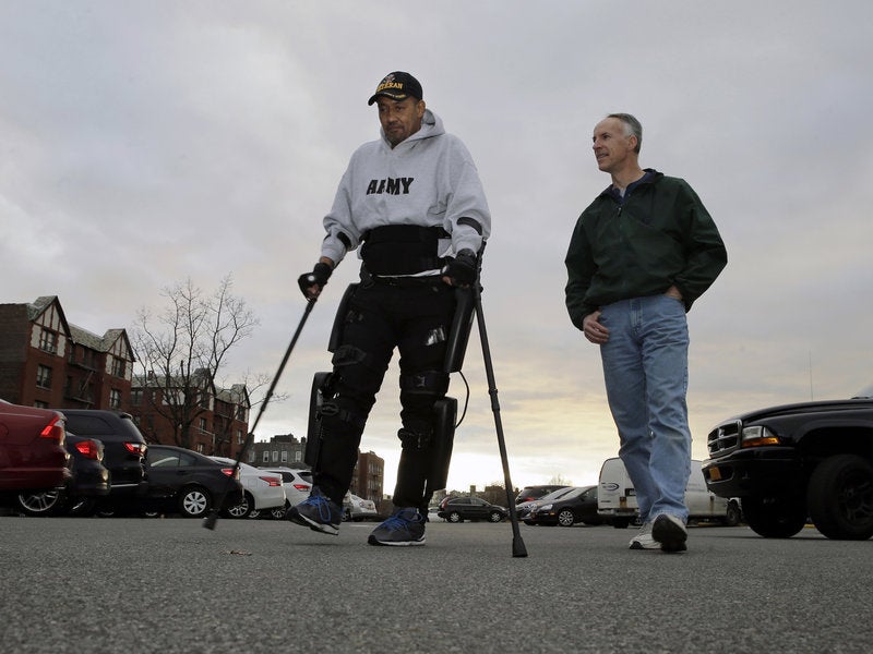 ReWalk Robotics service engineer Tom Coulter (right) looks on as paralyzed Army veteran Gene Laureano walks using a ReWalk device on Wednesday in the Bronx, N.Y.