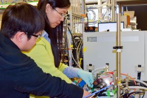 Graduate student Xiaofei Ye (left) helps postdoctoral scholar Liming Zhang adjust an experimental device that, confounding conventional wisdom, showed that heating metal oxide solar cells increased their efficiency. Credit Tom Abate