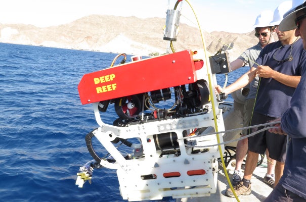 A robot outfitted with the new, human-like robotic "fingers" (lower left) is lowered into the Red Sea. Credit: Kevin Galloway, Wyss Institute at Harvard University.