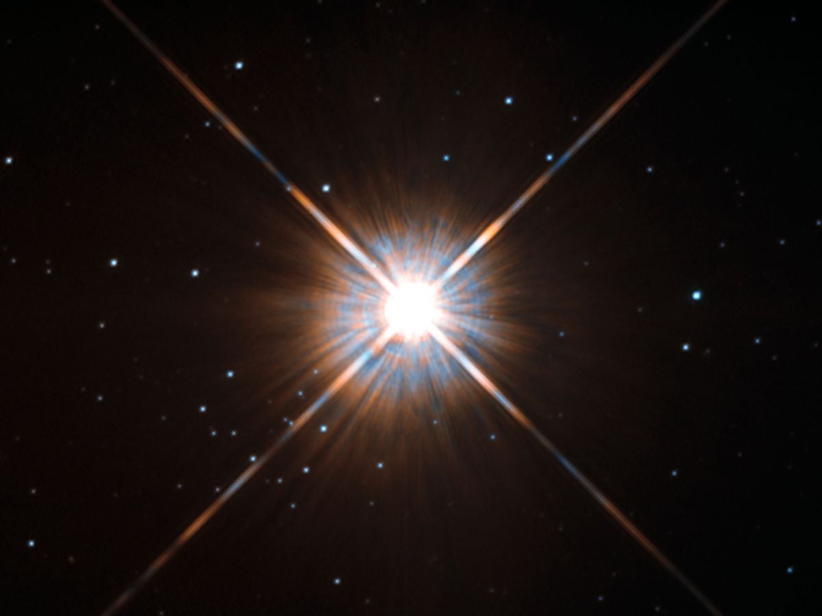 Shining brightly in this Hubble image is our closest stellar neighbour: Proxima Centauri. Proxima Centauri lies in the constellation of Centaurus (The Centaur), just over four light-years from Earth. Although it looks bright through the eye of Hubble, as you might expect from the nearest star to the Solar System, Proxima Centauri is not visible to the naked eye. Its average luminosity is very low, and it is quite small compared to other stars, at only about an eighth of the mass of the Sun. However, on occasion, its brightness increases. Proxima is what is known as a “flare star”, meaning that convection processes within the star’s body make it prone to random and dramatic changes in brightness. The convection processes not only trigger brilliant bursts of starlight but, combined with other factors, mean that Proxima Centauri is in for a very long life. Astronomers predict that this star will remain middle-aged — or a “main sequence” star in astronomical terms — for another four trillion years, some 300 times the age of the current Universe. These observations were taken using Hubble’s Wide Field and Planetary Camera 2 (WFPC2). Proxima Centauri is actually part of a triple star system — its two companions, Alpha Centauri A and B, lie out of frame. Although by cosmic standards it is a close neighbour, Proxima Centauri remains a point-like object even using Hubble’s eagle-eyed vision, hinting at the vast scale of the Universe around us.