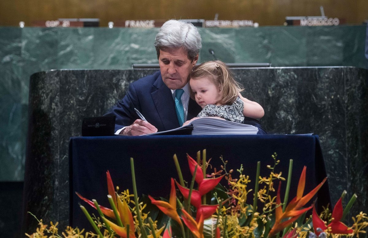 U.S. Secretary of State John Kerry signing the agreement with his granddaughter on his lap. UN