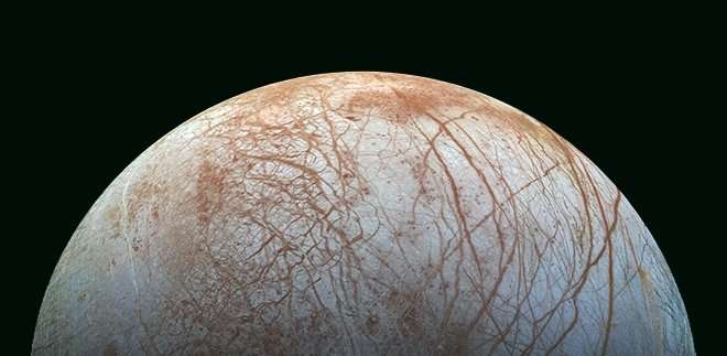 The surface of Europa, with bluish-white ice crisscrossed by reddish-brown streaks and cracks. Life on Europa may survive far beneath that icy shell by living off nuclear energy.