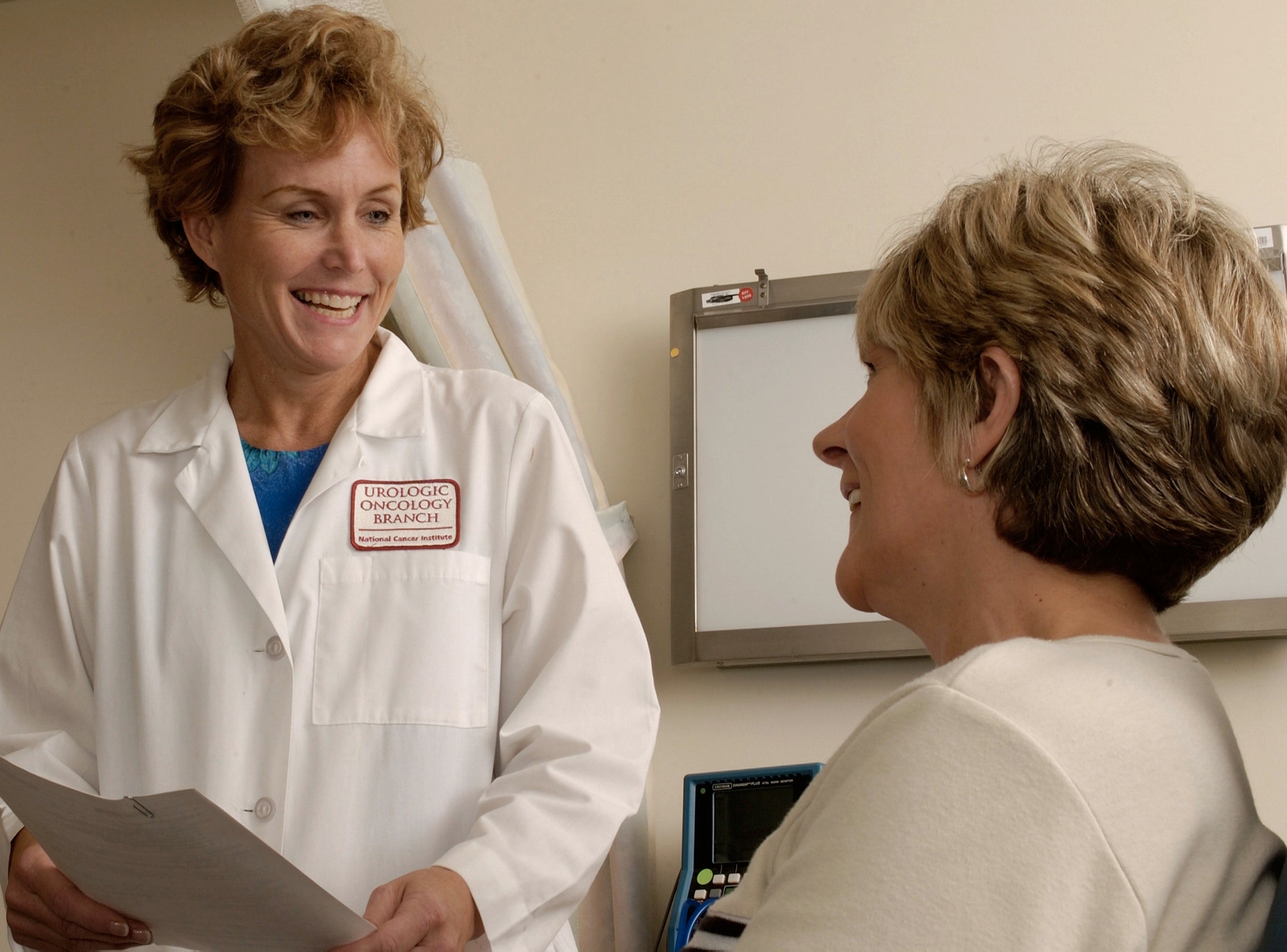 A white female doctor discussing medical data with a white female patient. 