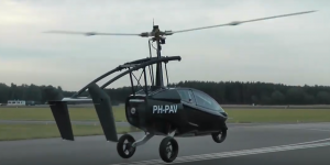 A Pal-V flying car begins to take flight from an airport runway